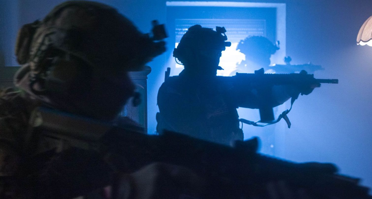 Three special operations soldiers in full gear methodically clearing a room, showcasing tactical precision and teamwork.