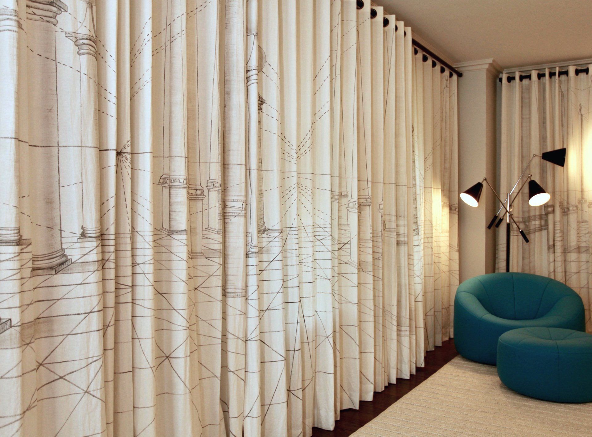 A blue chair is sitting in front of a wall with curtains