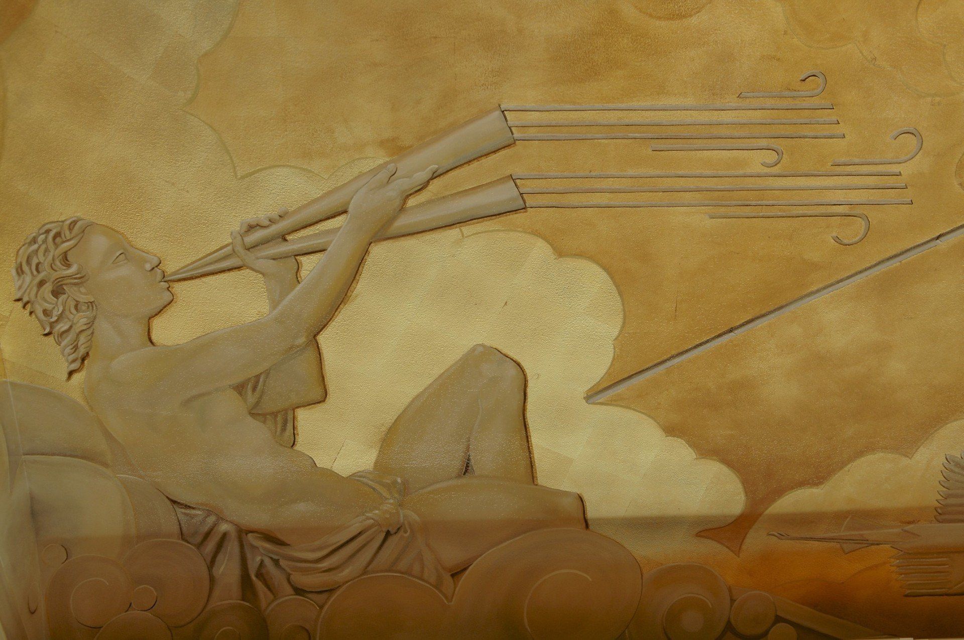 A statue of a man holding a telescope on a wall.