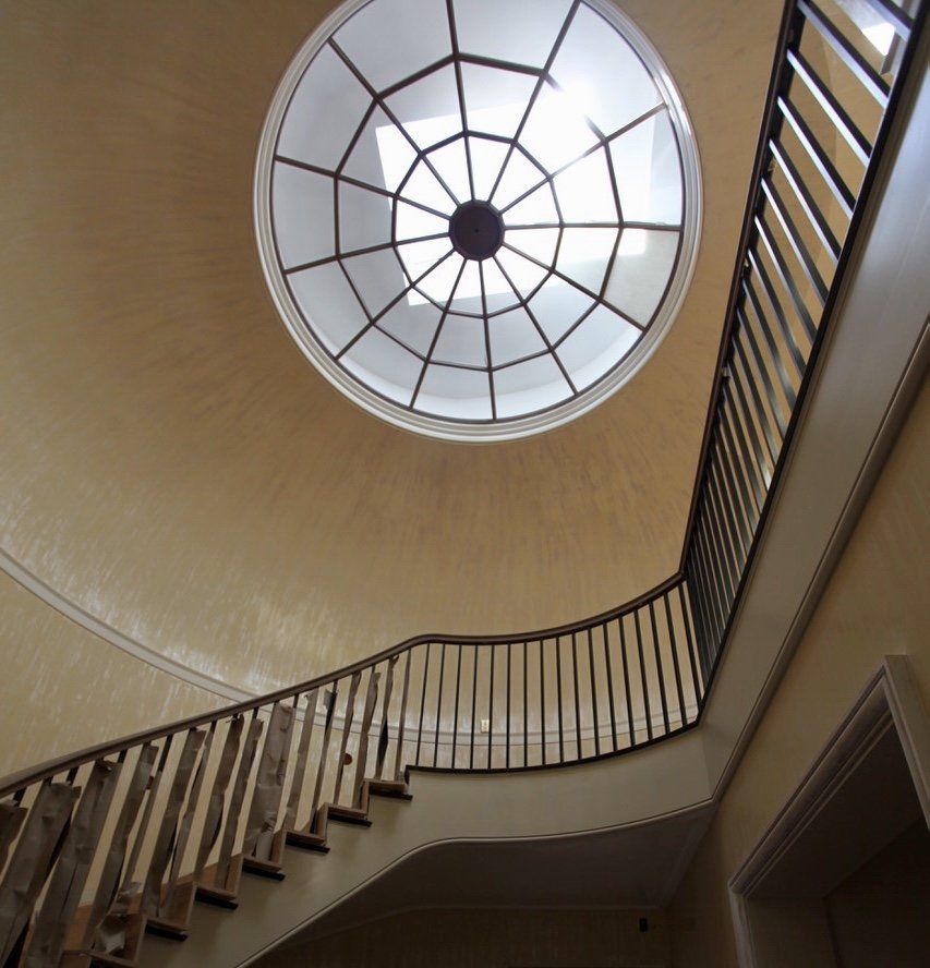 Looking up at a spiral staircase with a dome above it