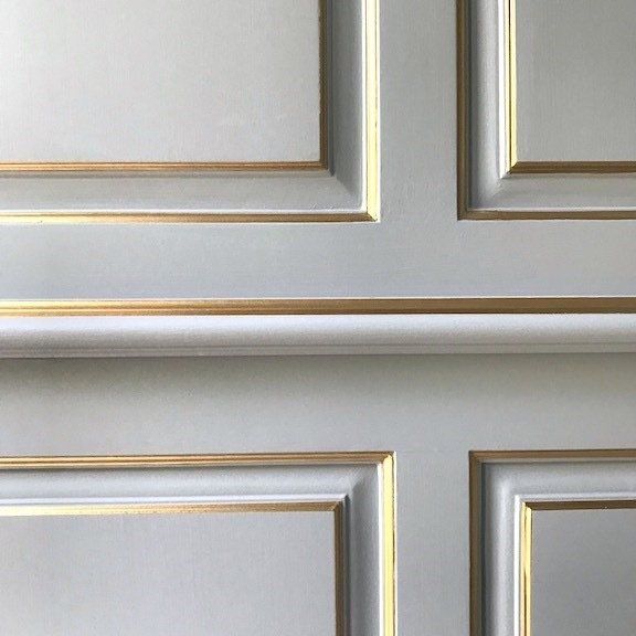 A close up of a white wall with gold trim.