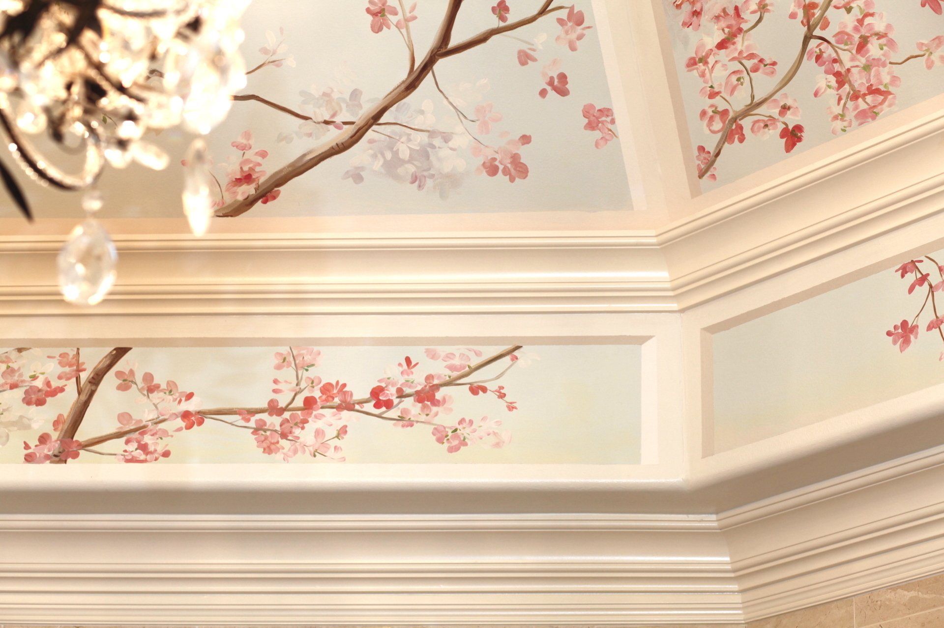 A ceiling with cherry blossoms painted on it and a chandelier hanging from it.
