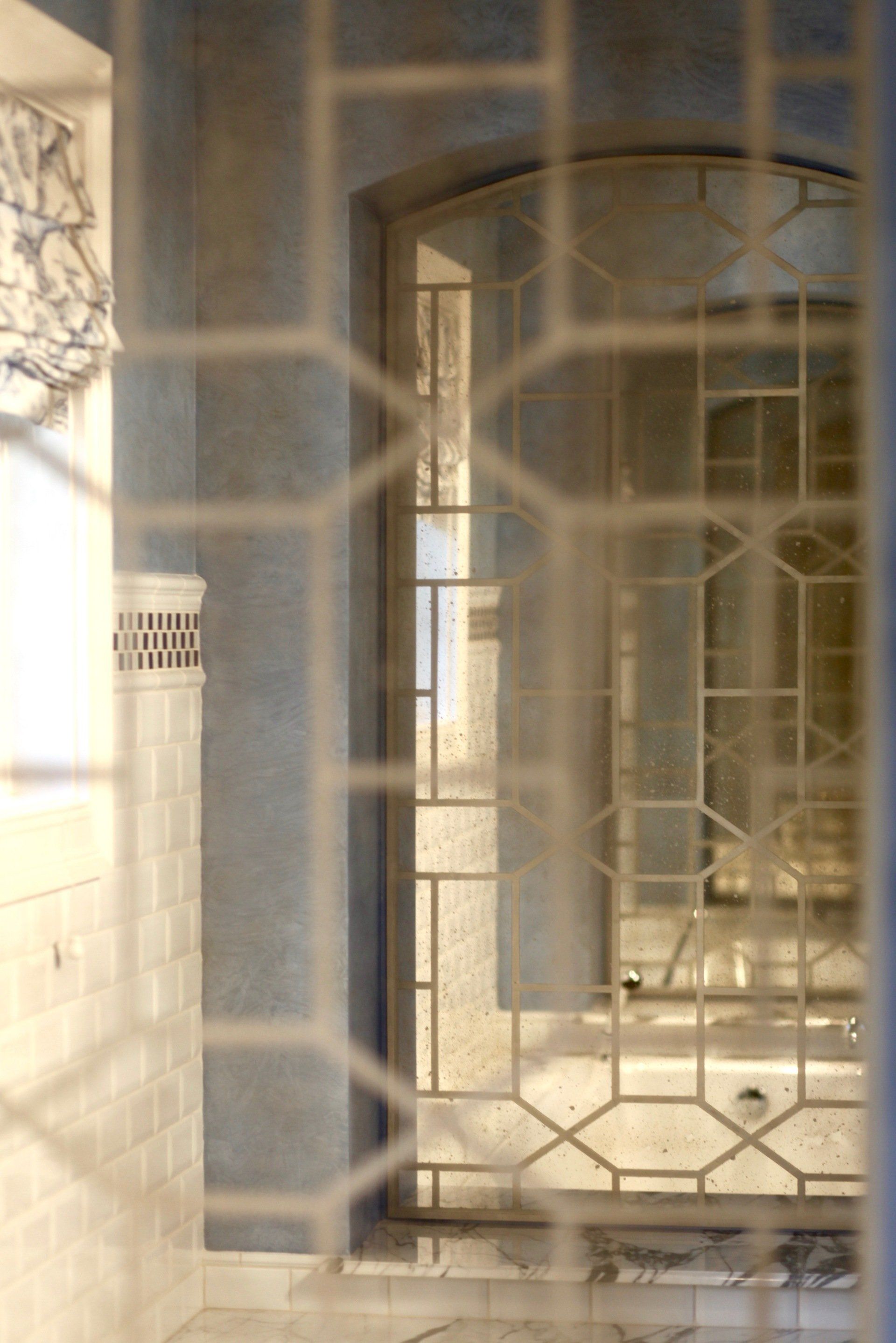 A door with a geometric design is behind a fence.