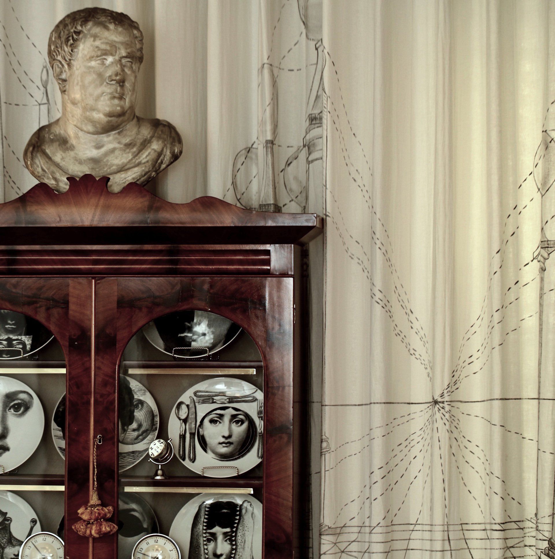A statue of a man sits on top of a cabinet filled with plates