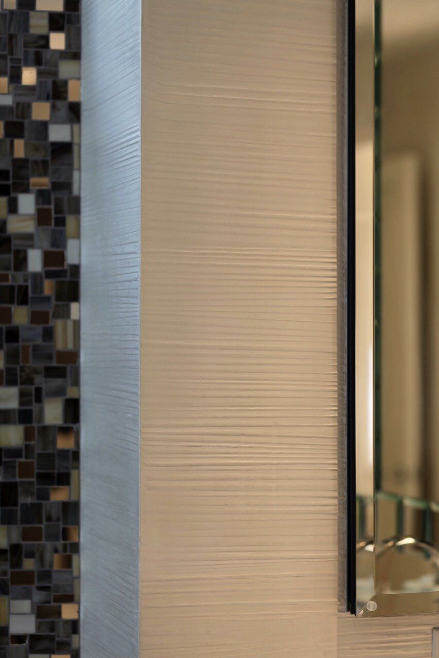 A bathroom with a mirror and a tiled wall
