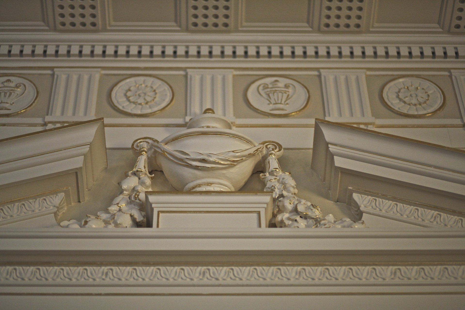 There is a statue of a vase on the ceiling of a building.