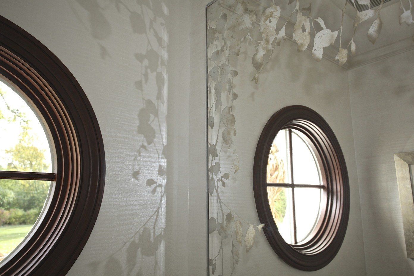 A bathroom with two round windows and a mirror