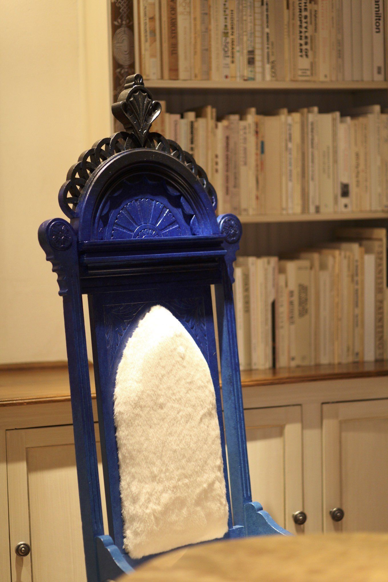 A blue chair is sitting in front of a bookshelf with books on it