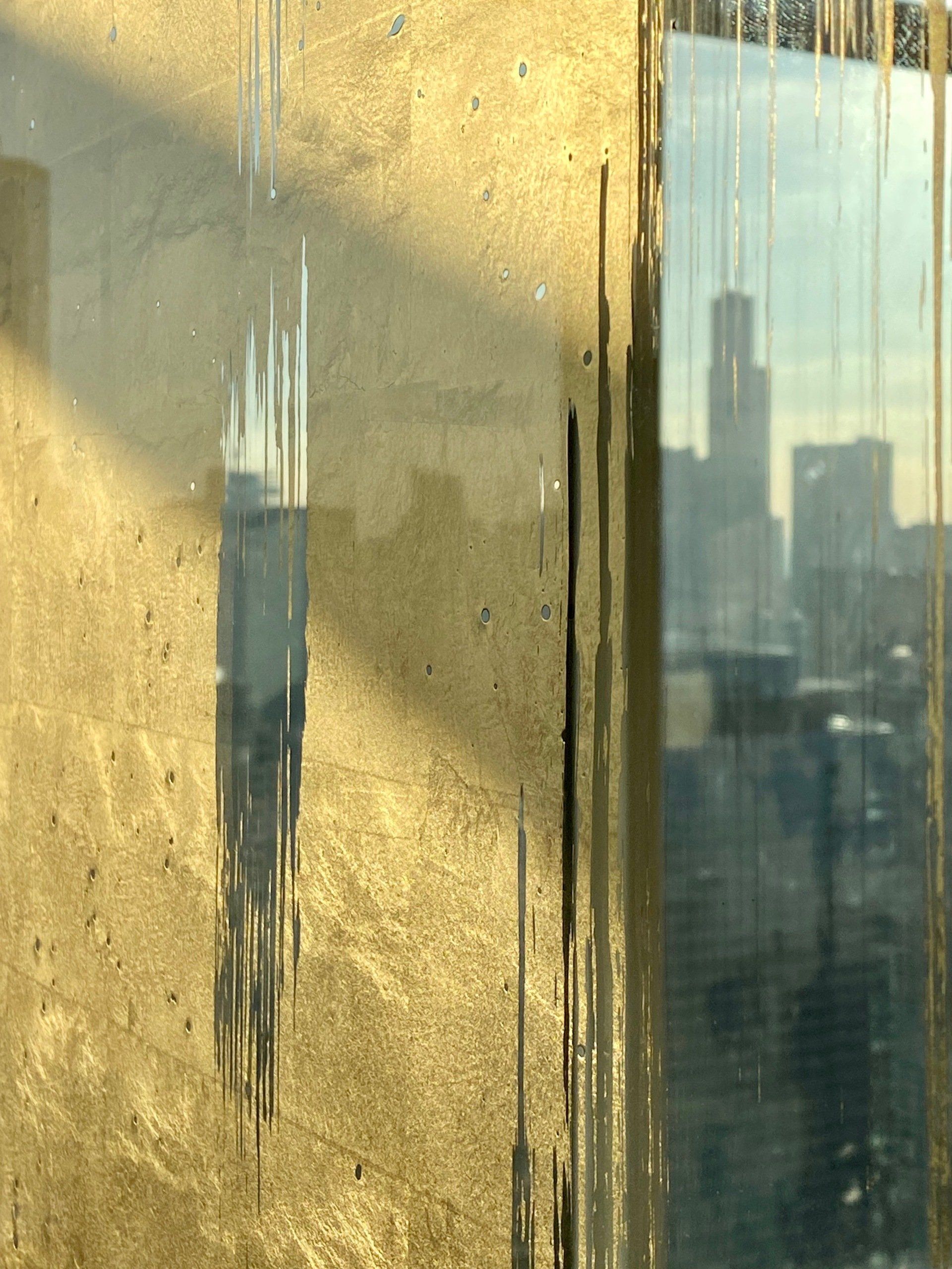 A close up of a gold wall with a reflection of a city skyline