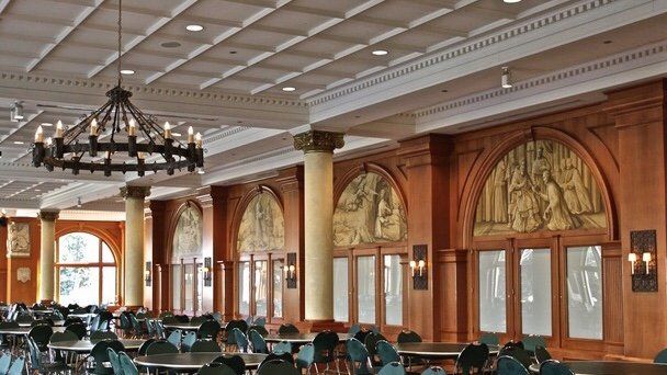 A large dining room with tables and chairs and a chandelier hanging from the ceiling.