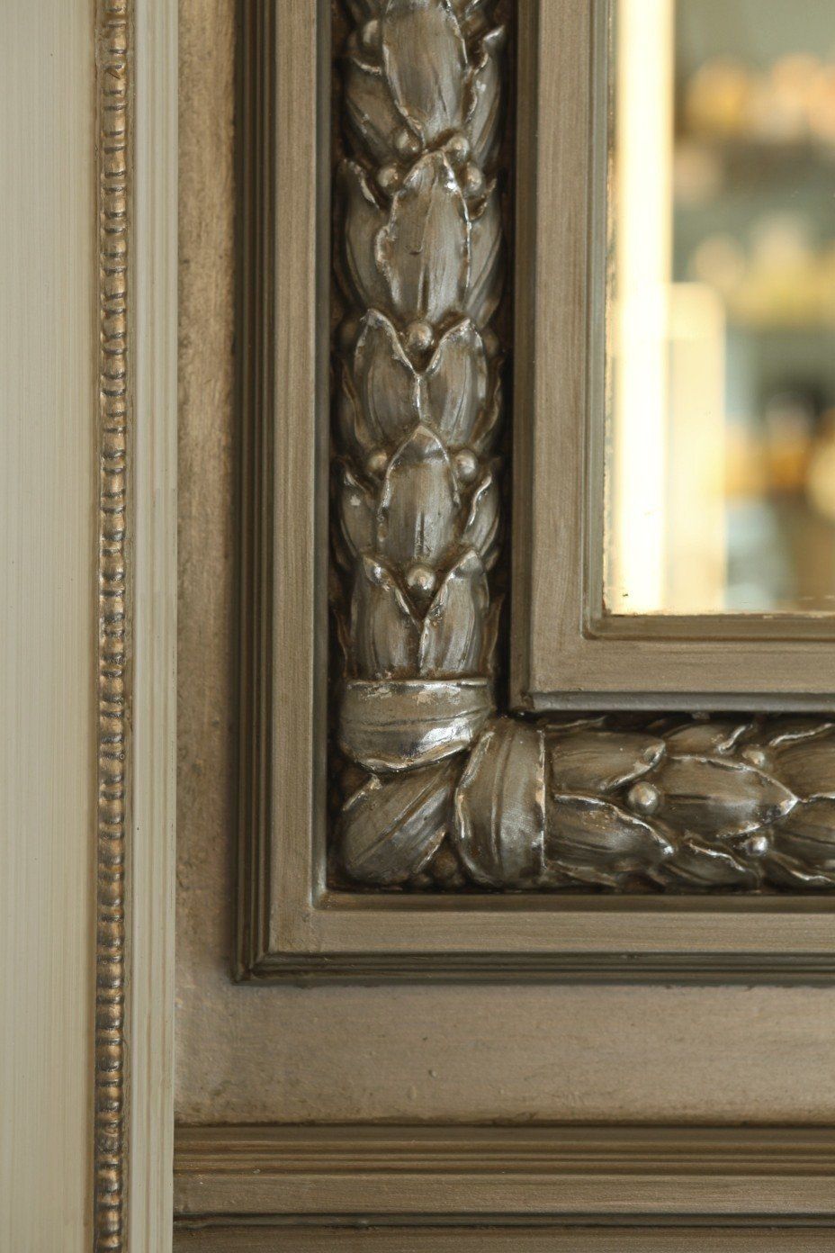 A close up of a mirror with a fancy frame on a wall.