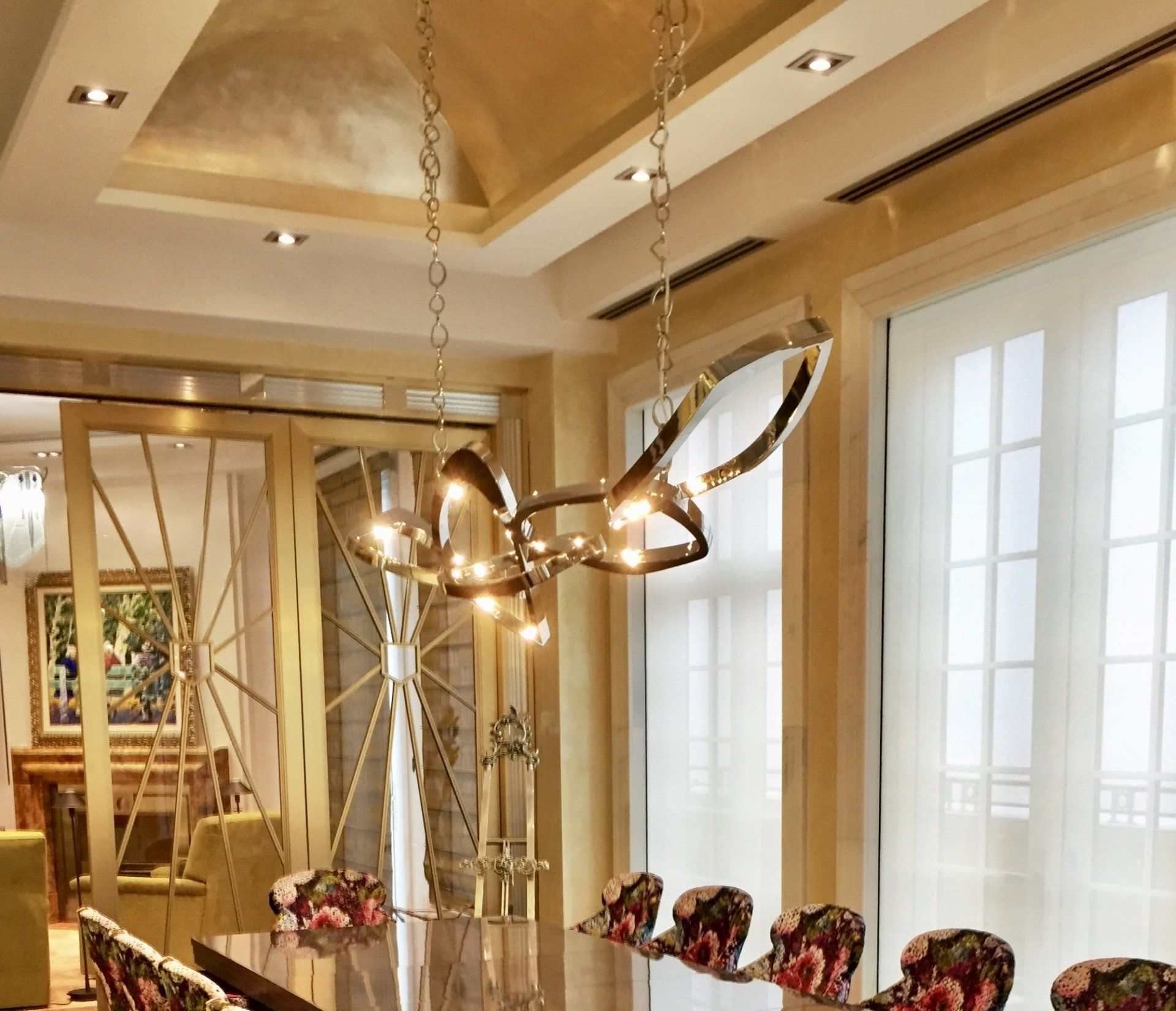 A dining room with a long table and chairs and a chandelier hanging from the ceiling
