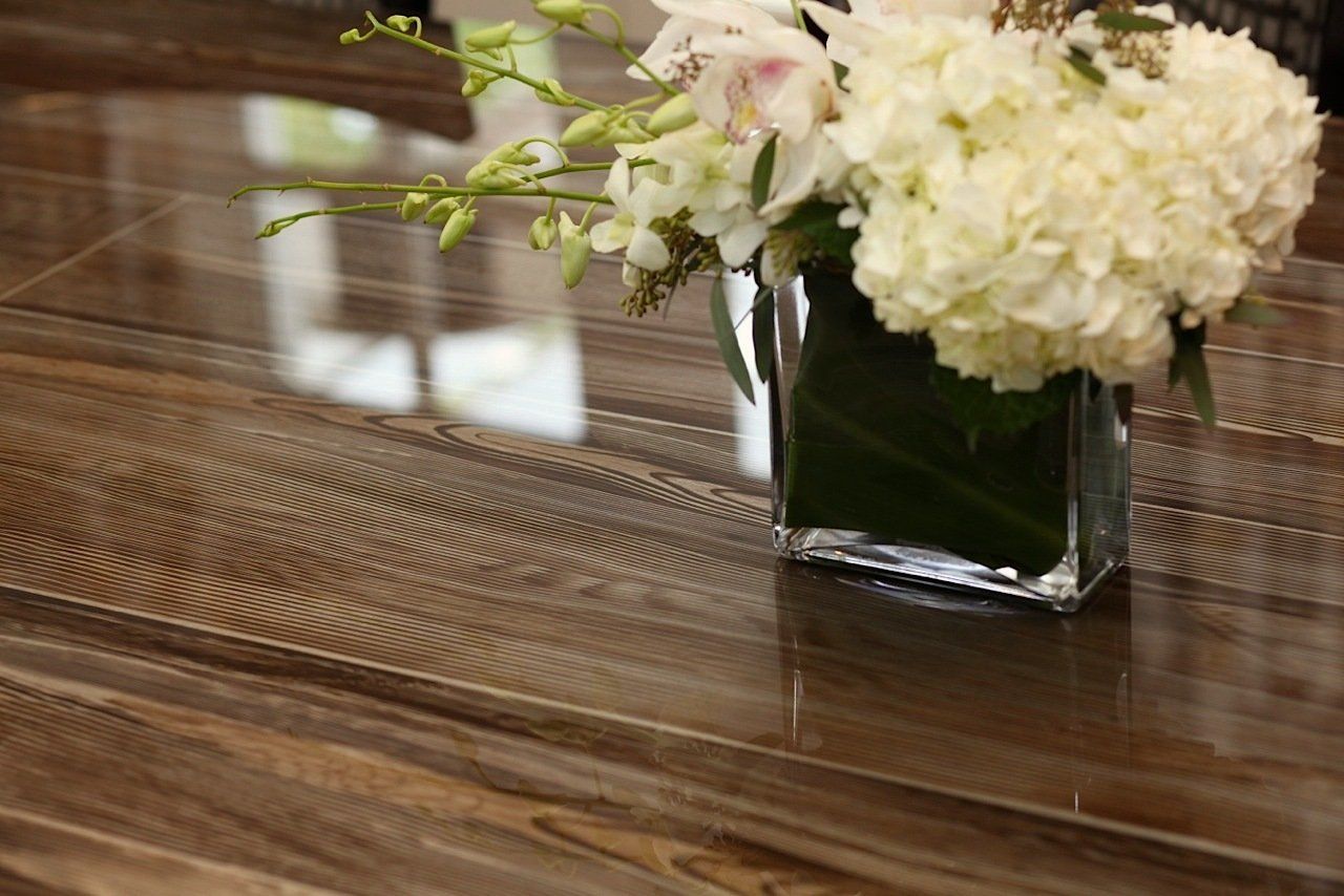 A vase of flowers is sitting on a wooden table.