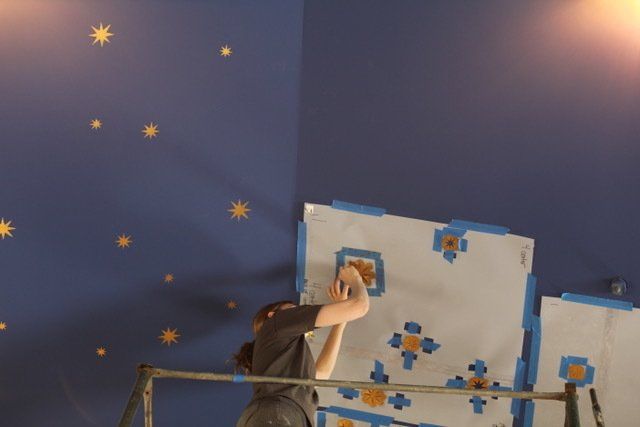 A person is painting a wall with stars on it