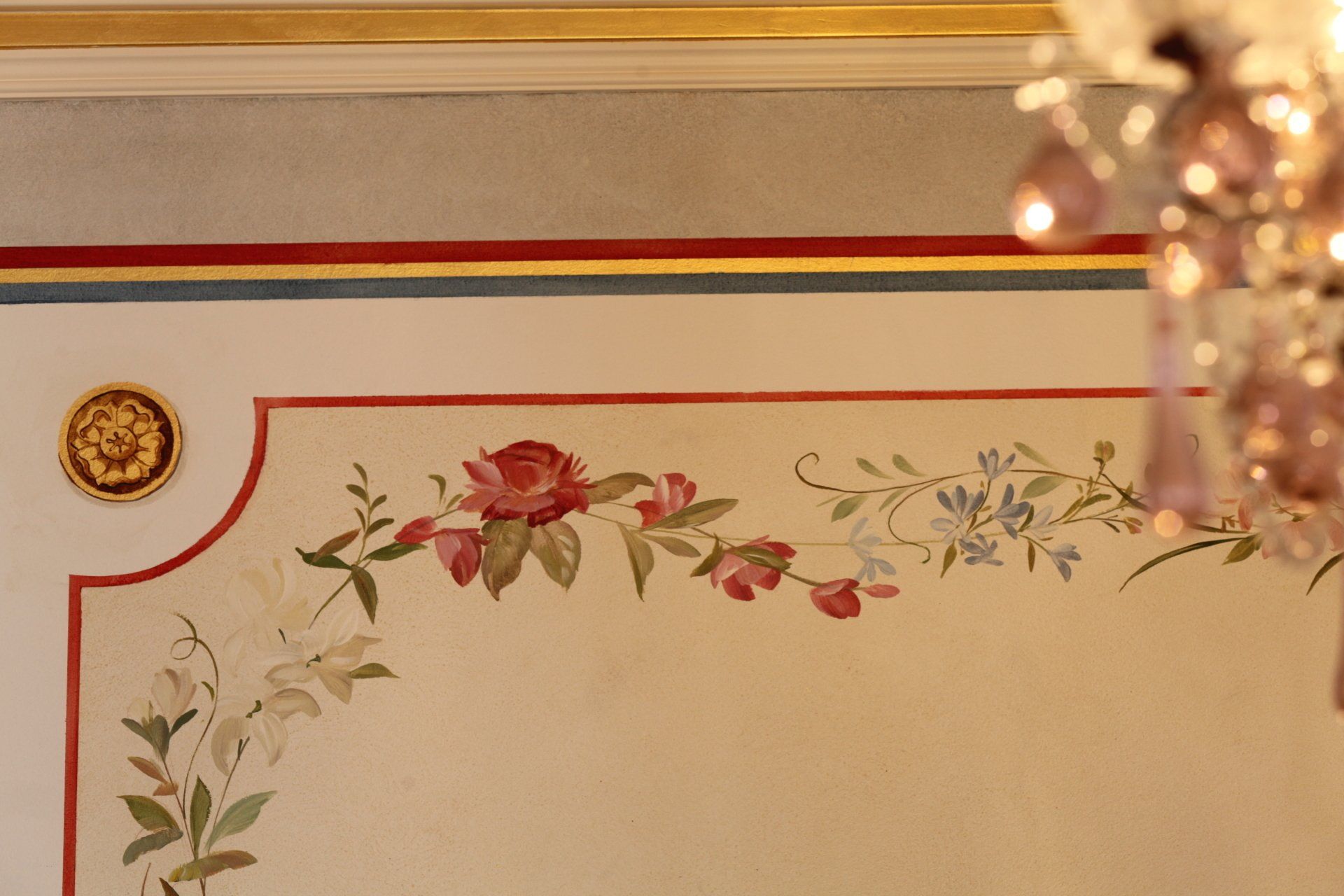 A wall with flowers painted on it and a chandelier hanging from the ceiling