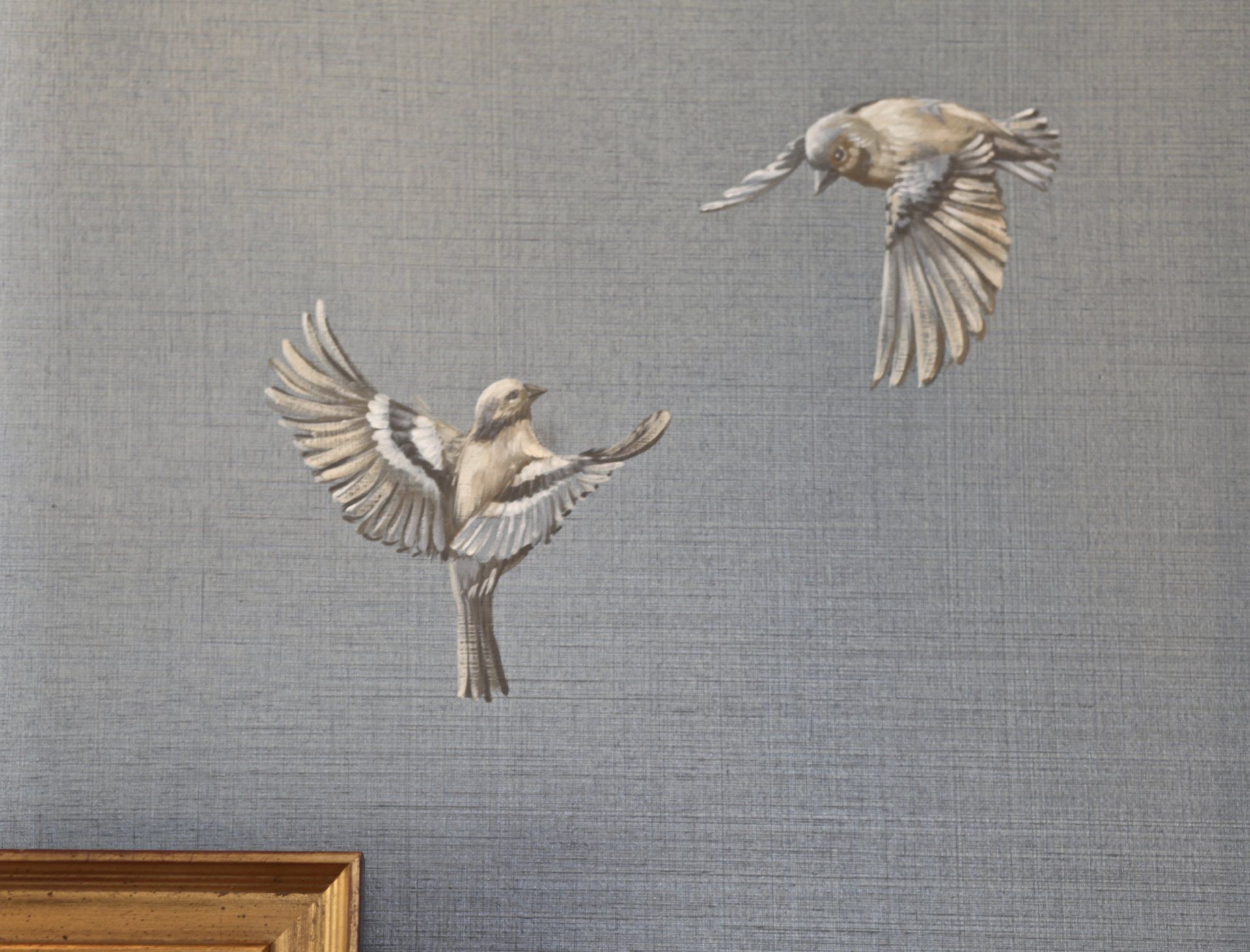 Two birds are flying in the air on a wall.