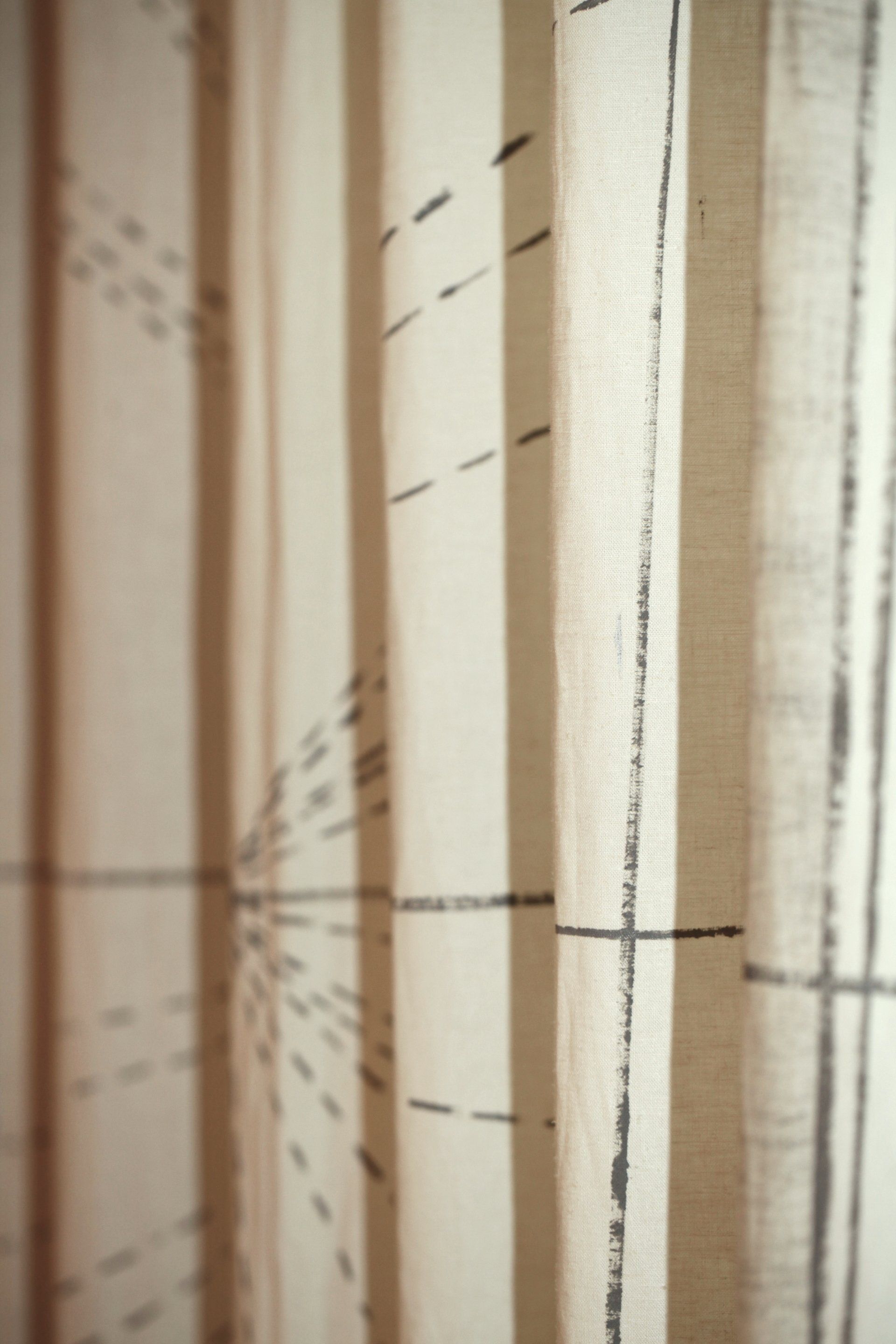 A close up of a white curtain with black lines on it.
