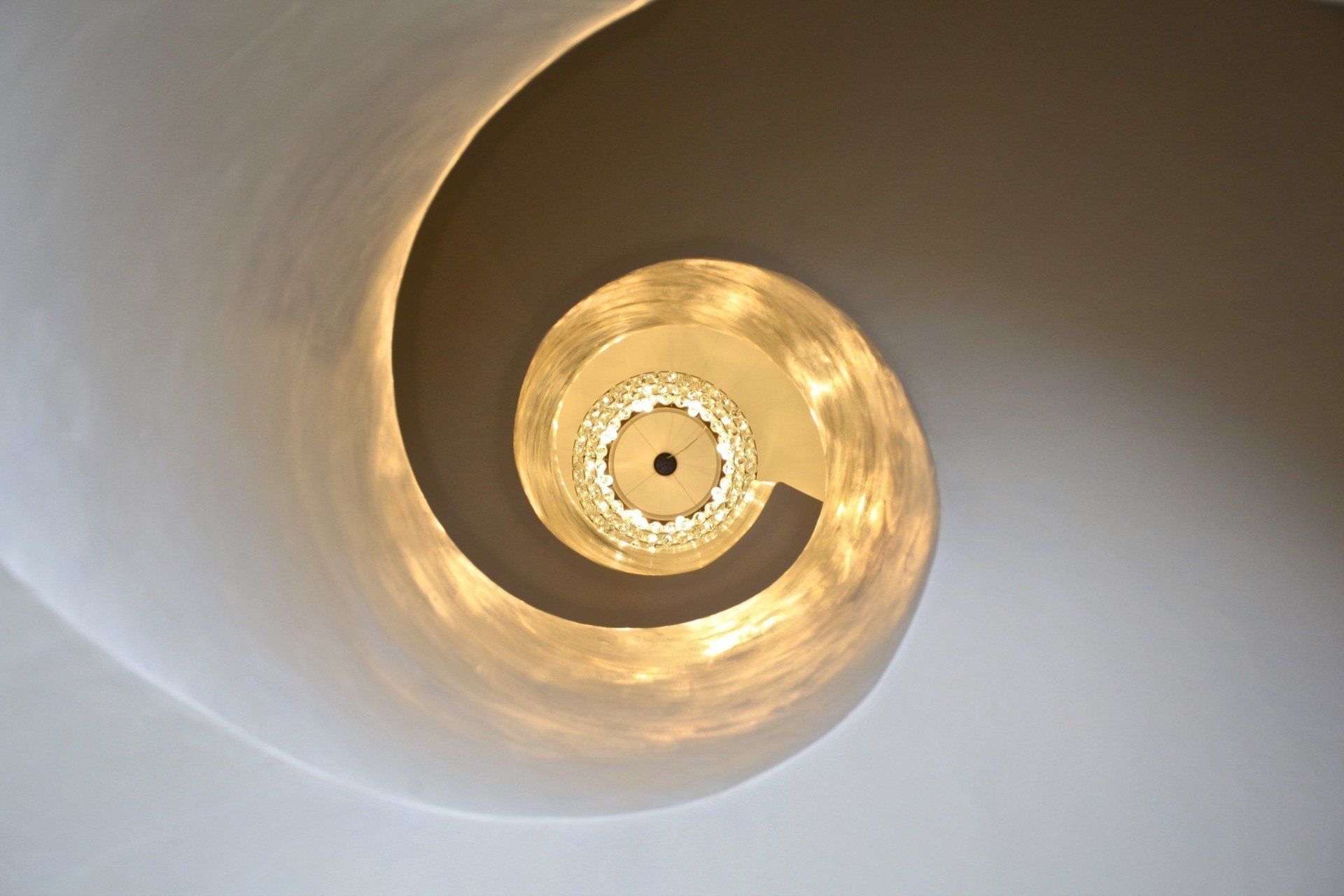 Looking up at a spiral staircase with lights on it