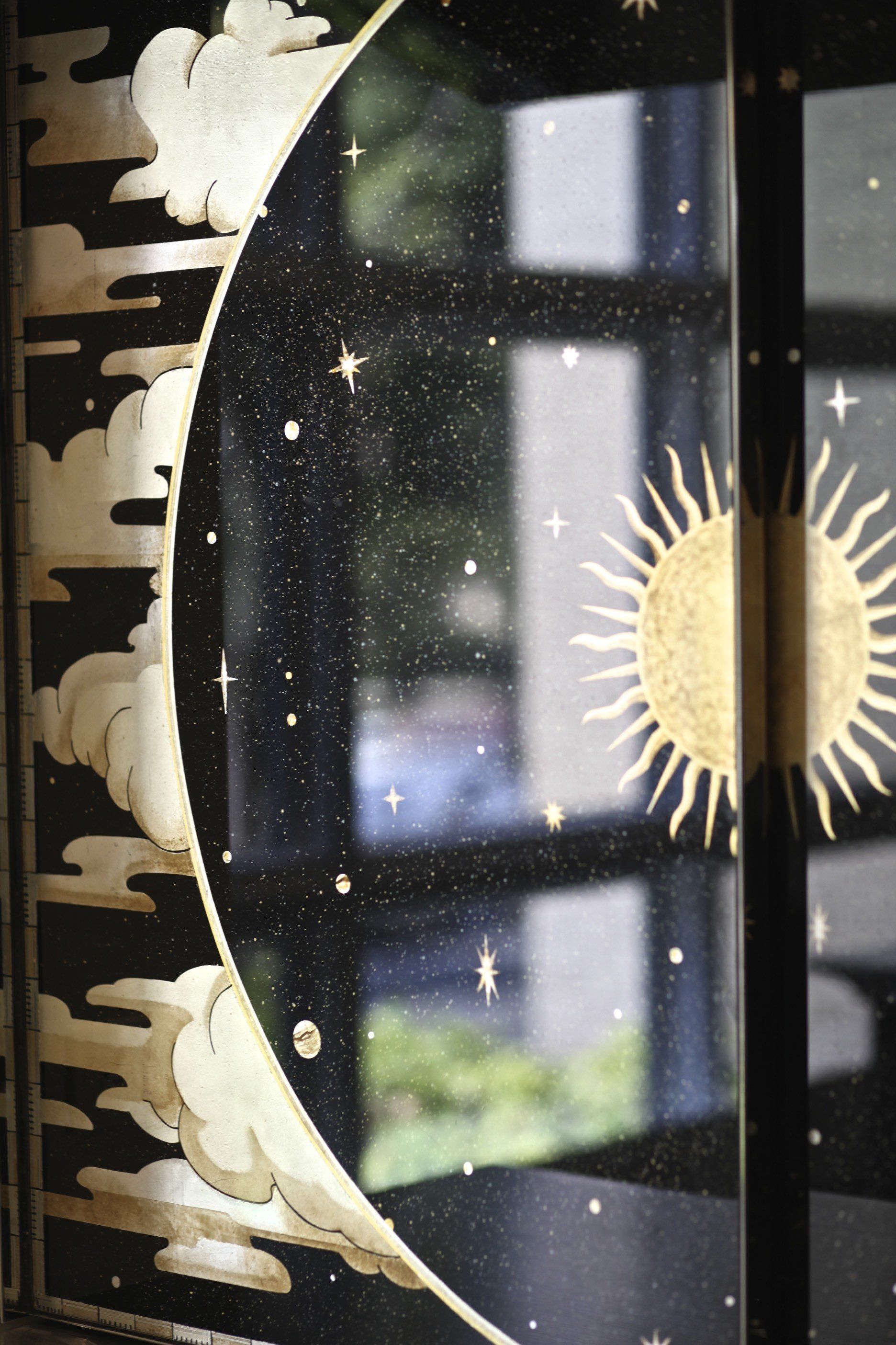 A black and gold painting of a crescent moon and sun