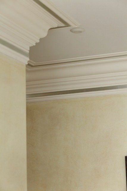 A close up of a ceiling with molding in a room.