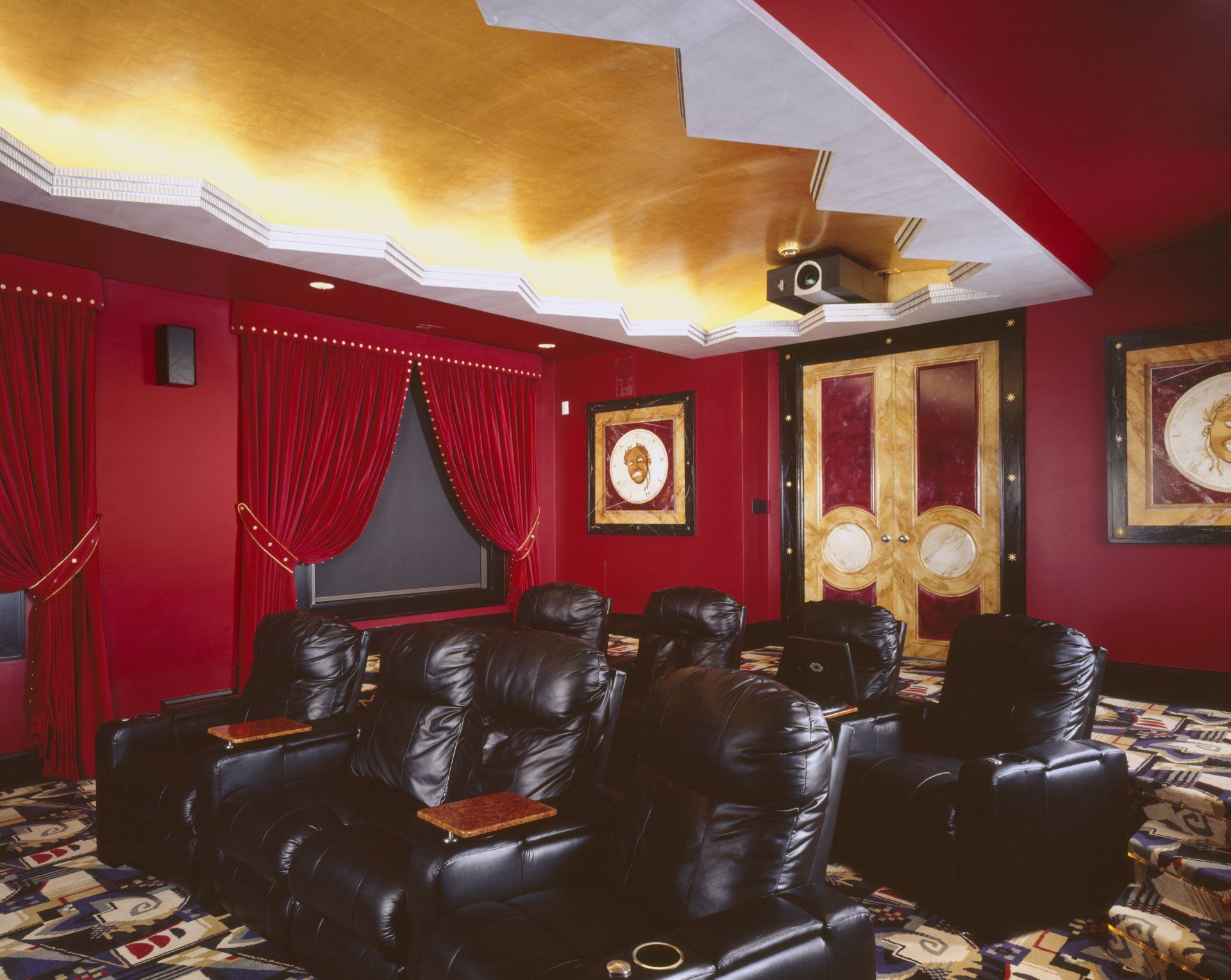 A home theater with red walls and black leather seats