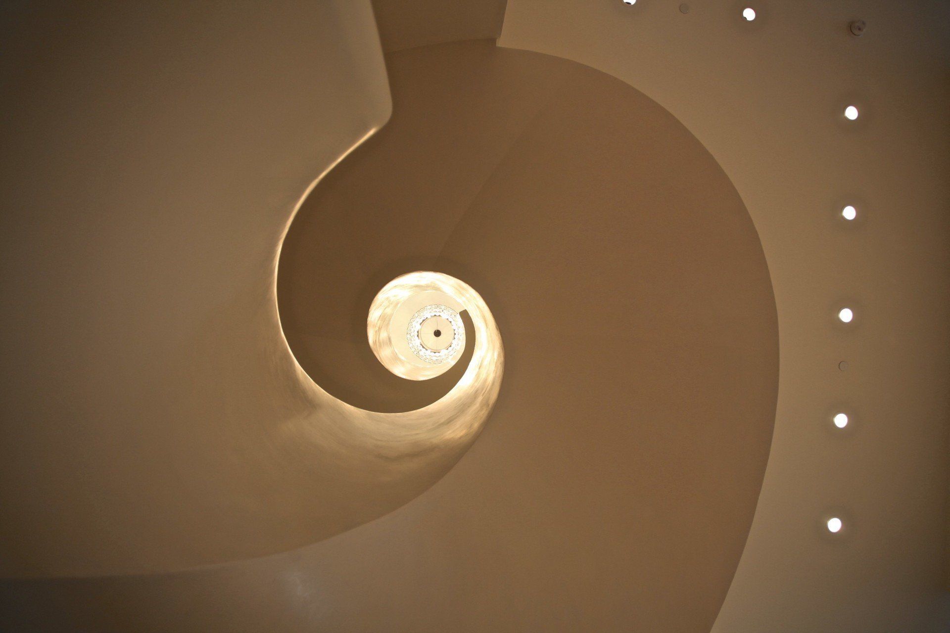 Looking up at a spiral staircase with lights on the ceiling