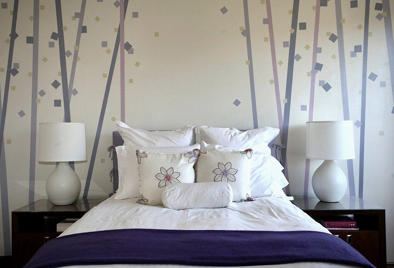 A bed with white sheets and a purple blanket