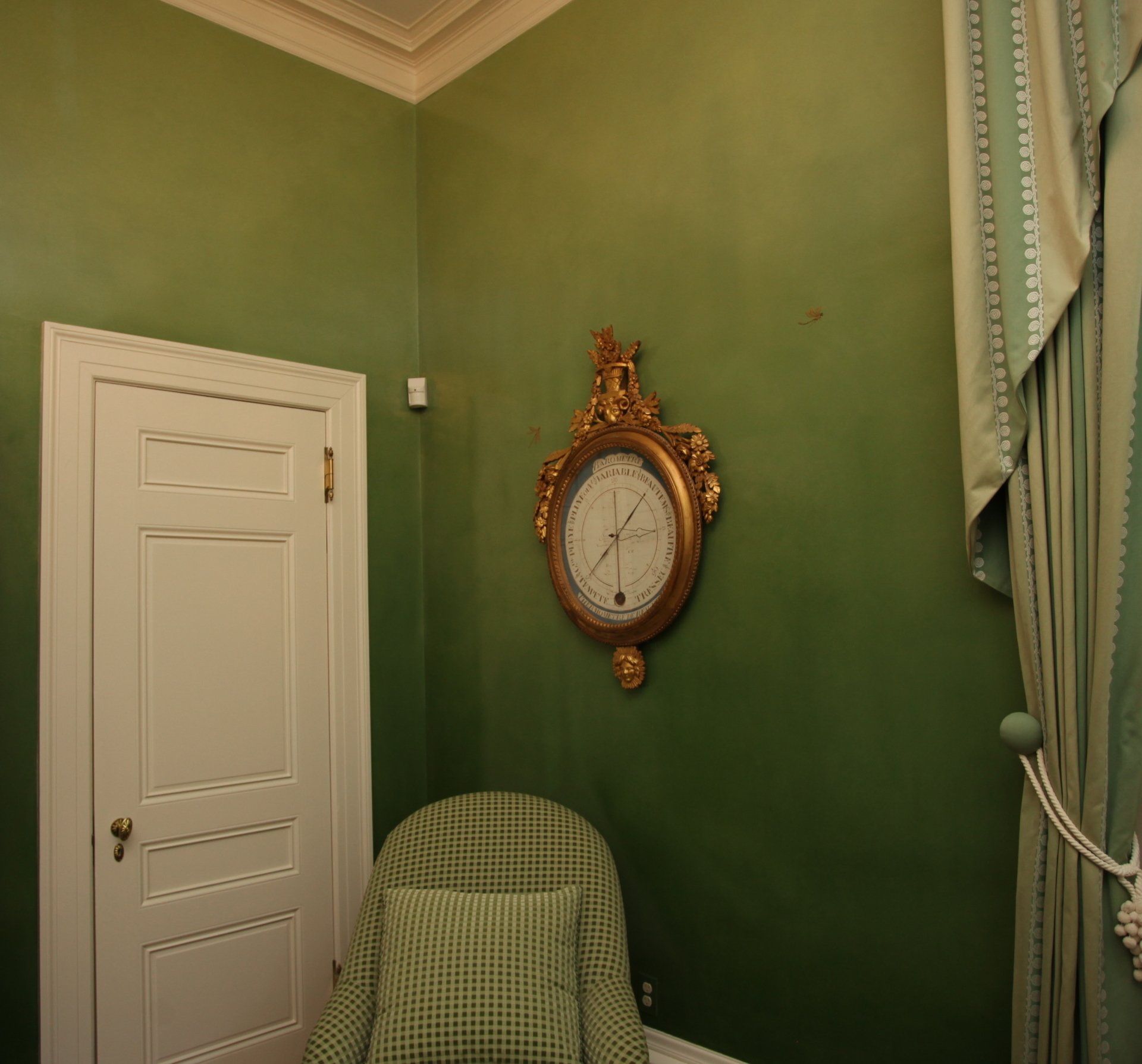 A green room with a chair and a clock on the wall