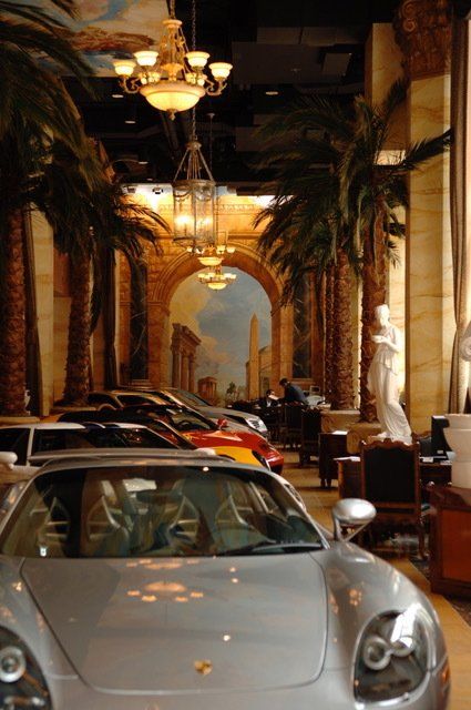 A row of cars are parked in a hallway with palm trees