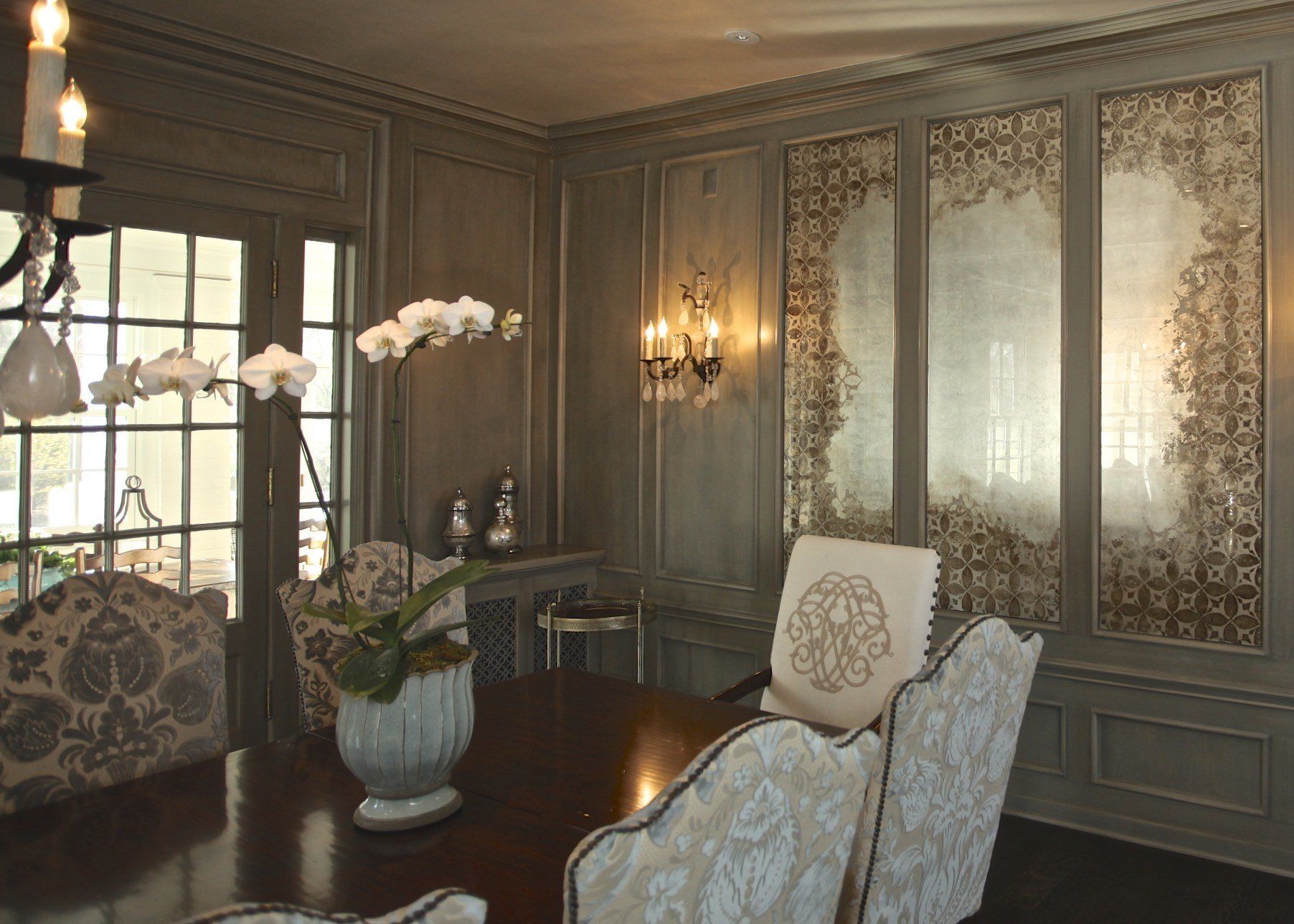 A dining room with a table and chairs and a vase of flowers on the table.