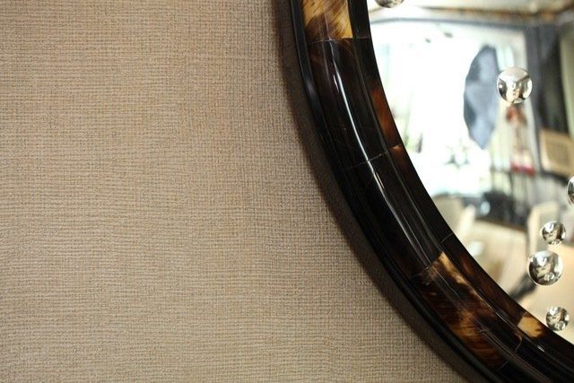 A round mirror with a brown frame is hanging on a wall