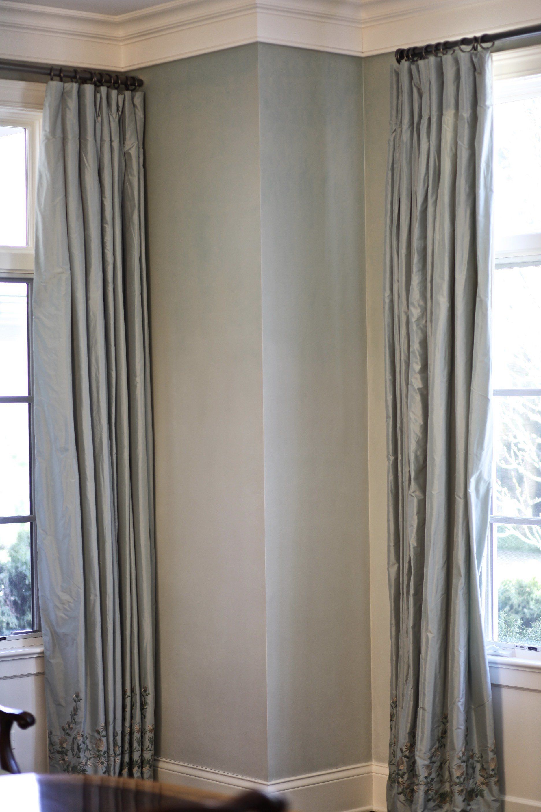 A corner of a room with curtains and a window.