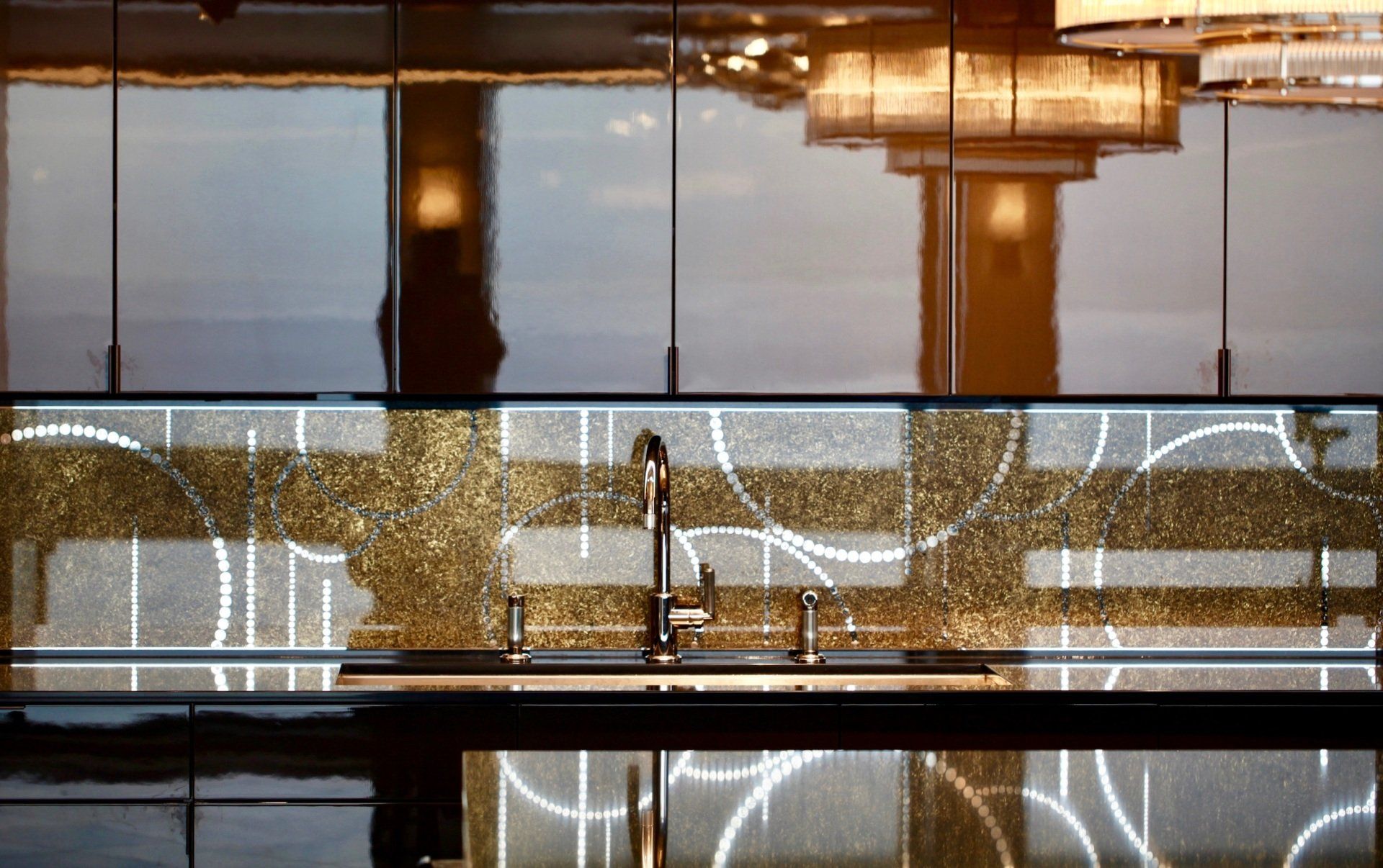 A kitchen with a sink , cabinets and a reflection of a chandelier.
