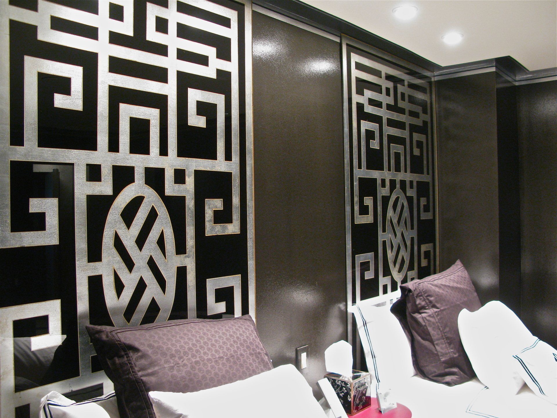 A bedroom with a greek key pattern on the wall