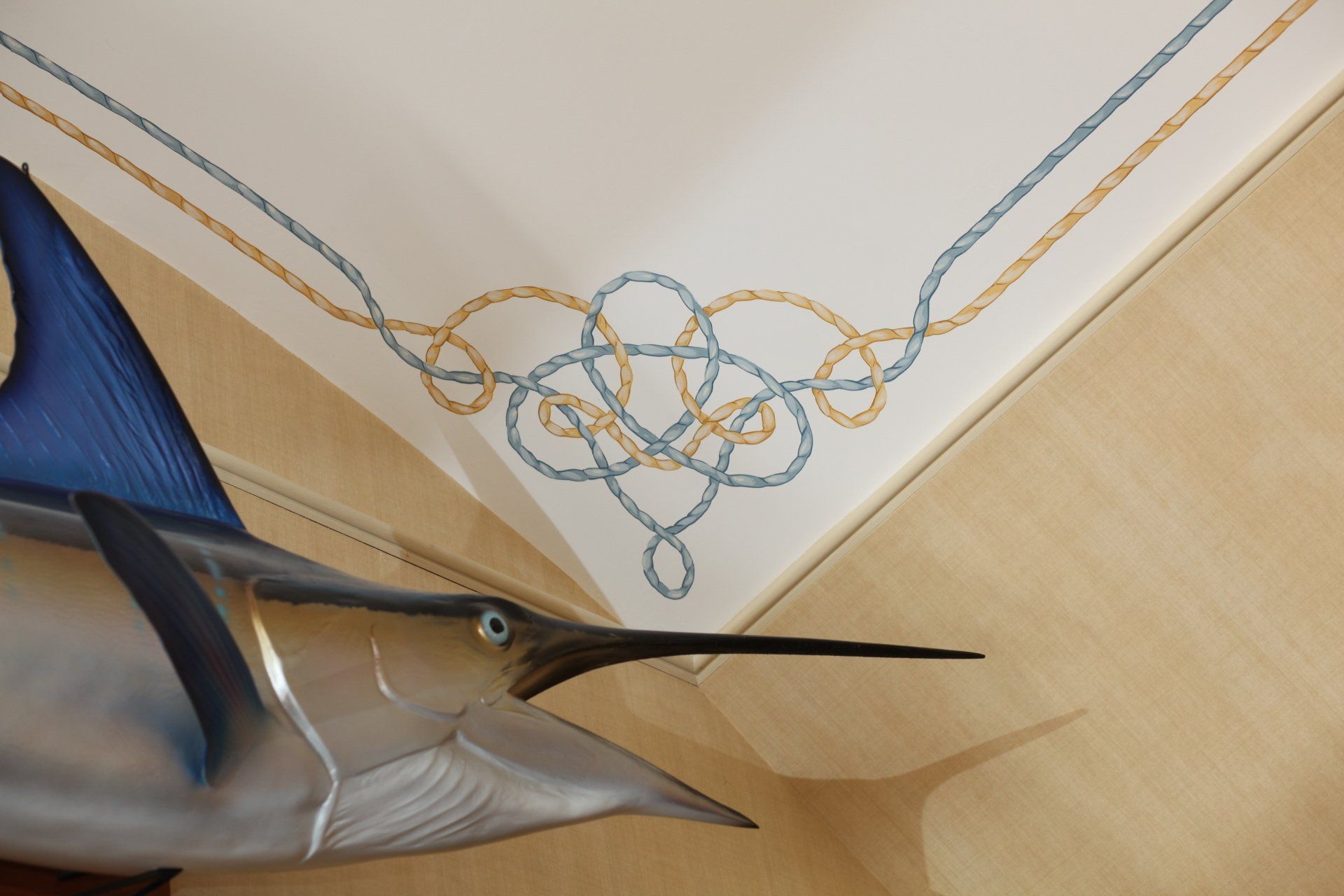 A fish is hanging from the ceiling with a rope design