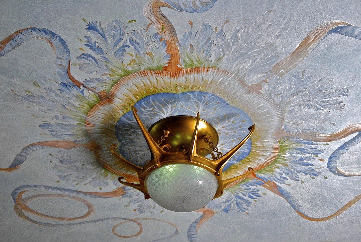 A light hanging from a ceiling with a painting on it