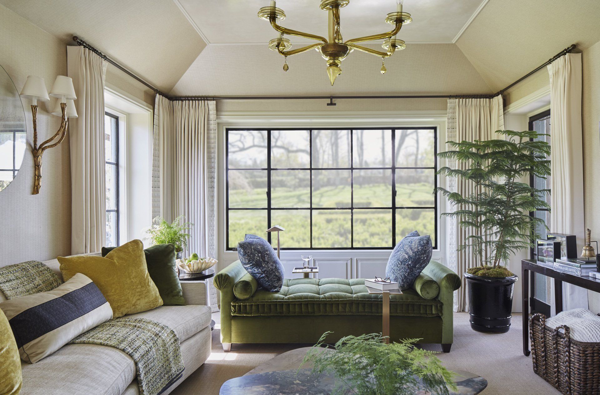 A living room with a green couch and a chandelier.
