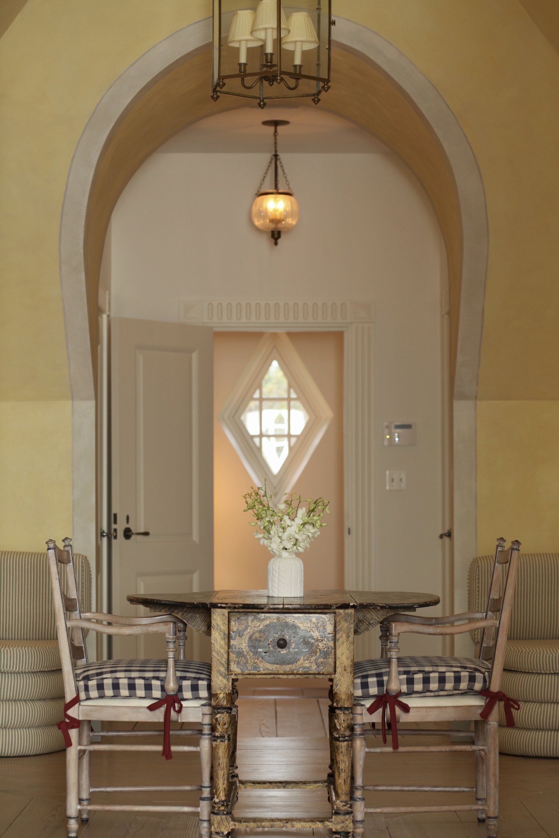 A room with two chairs and a table with a vase of flowers on it