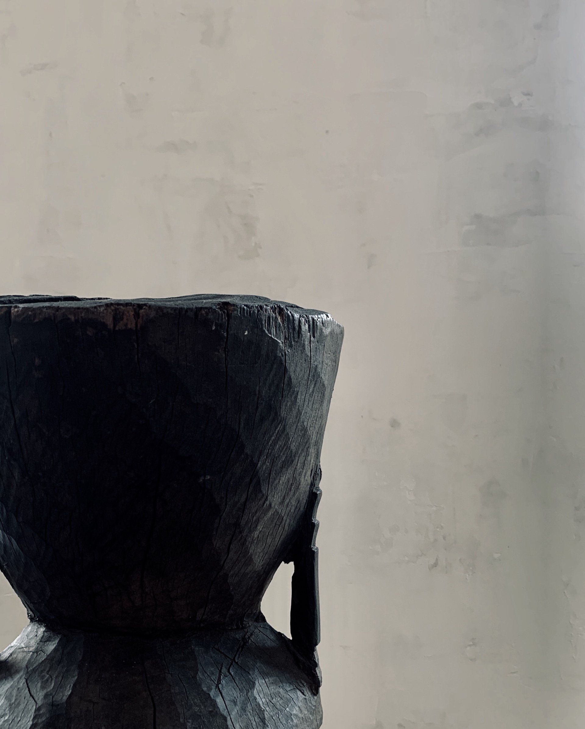 A black bowl is sitting on a table in front of a white wall.