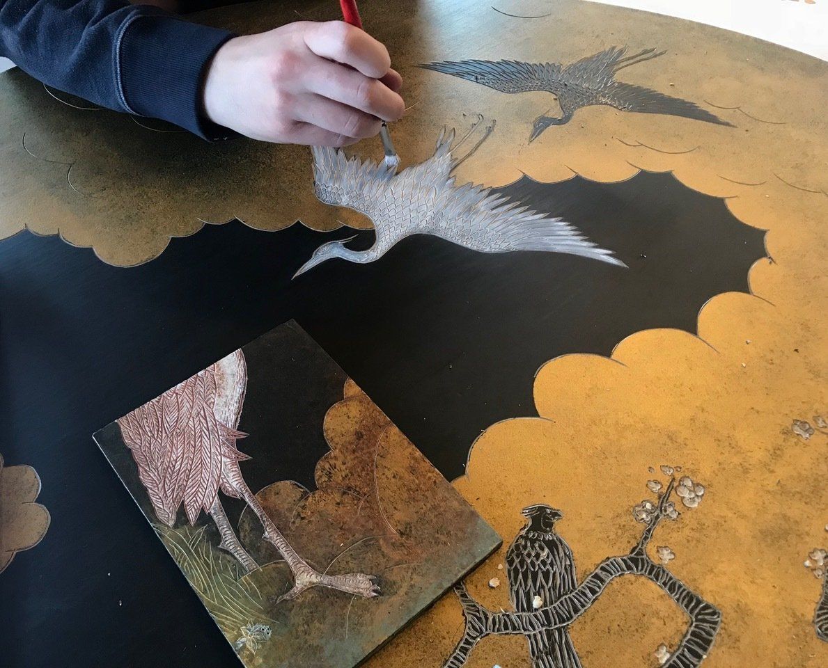 A person is painting a picture of a bird on a table