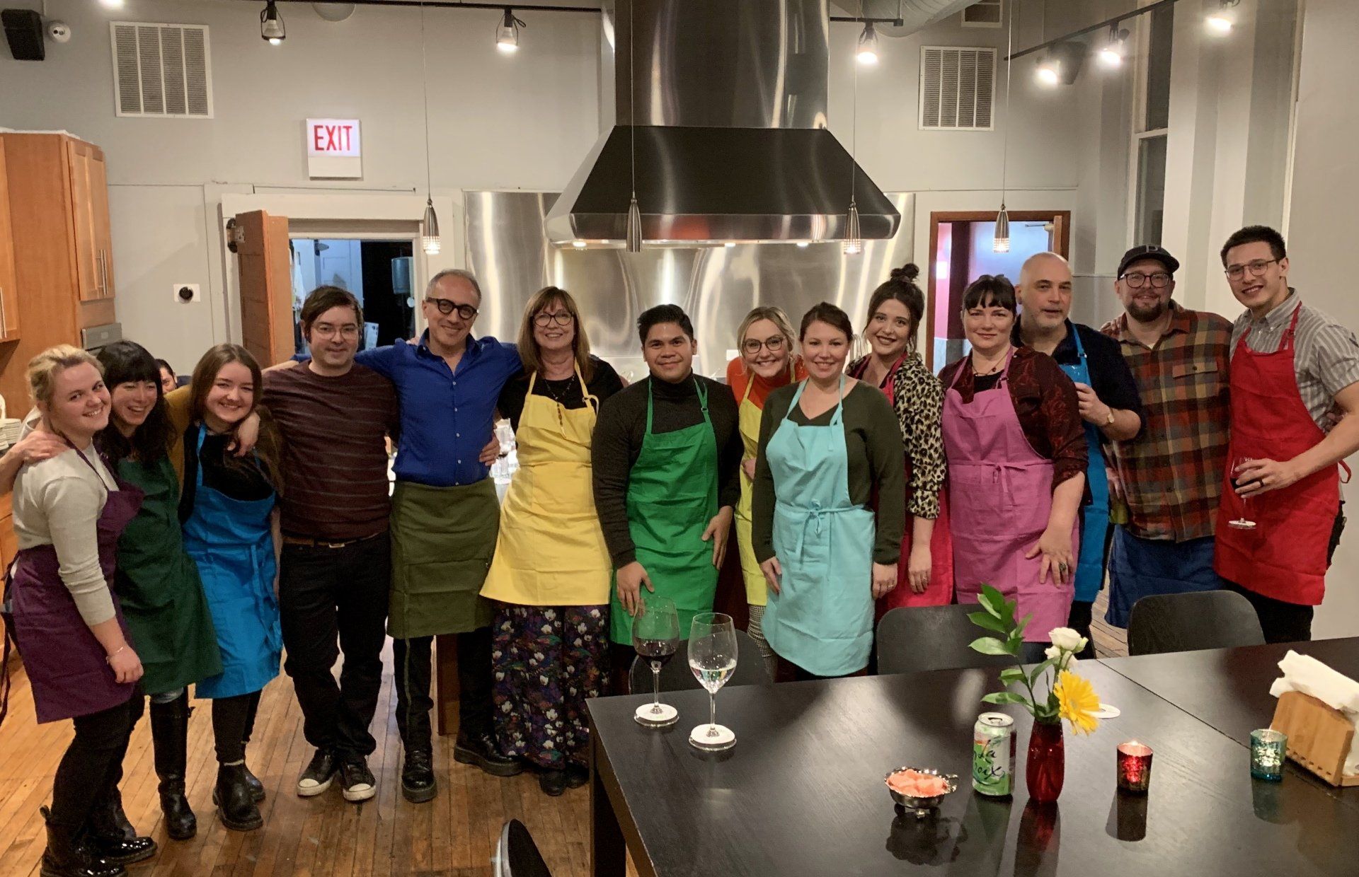 A group of people wearing aprons are posing for a picture in a kitchen.
