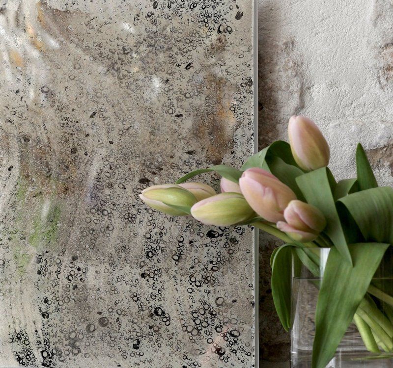 A vase of flowers sits next to a mirror