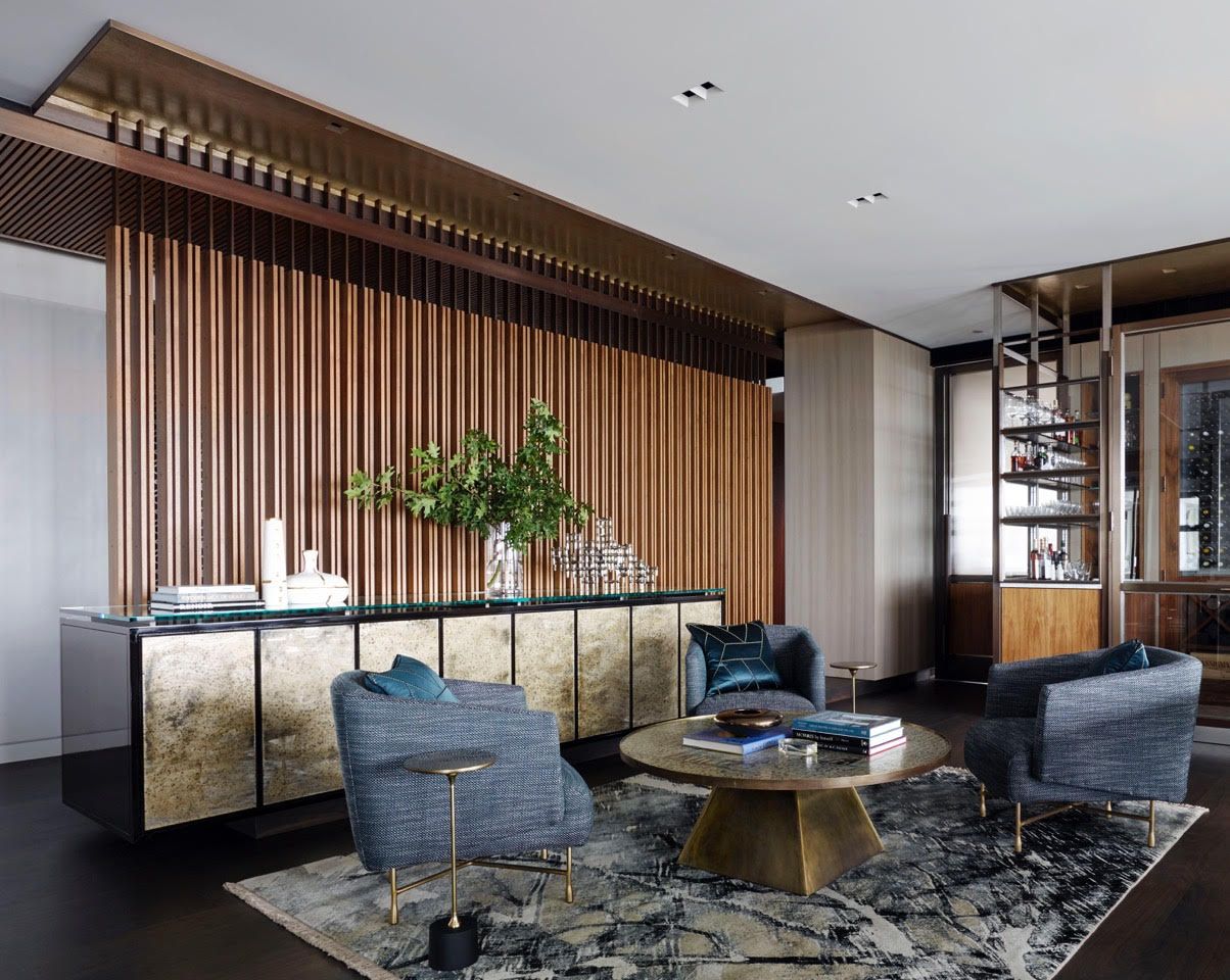 A living room with a wooden wall , chairs , a table and a rug.