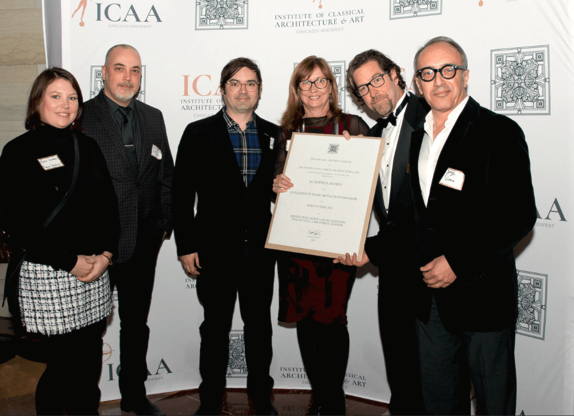 A group of people standing in front of a wall that says icaa
