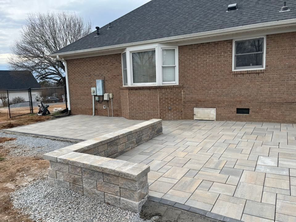 Brick home with newly constructed stone patio and low retaining wall.