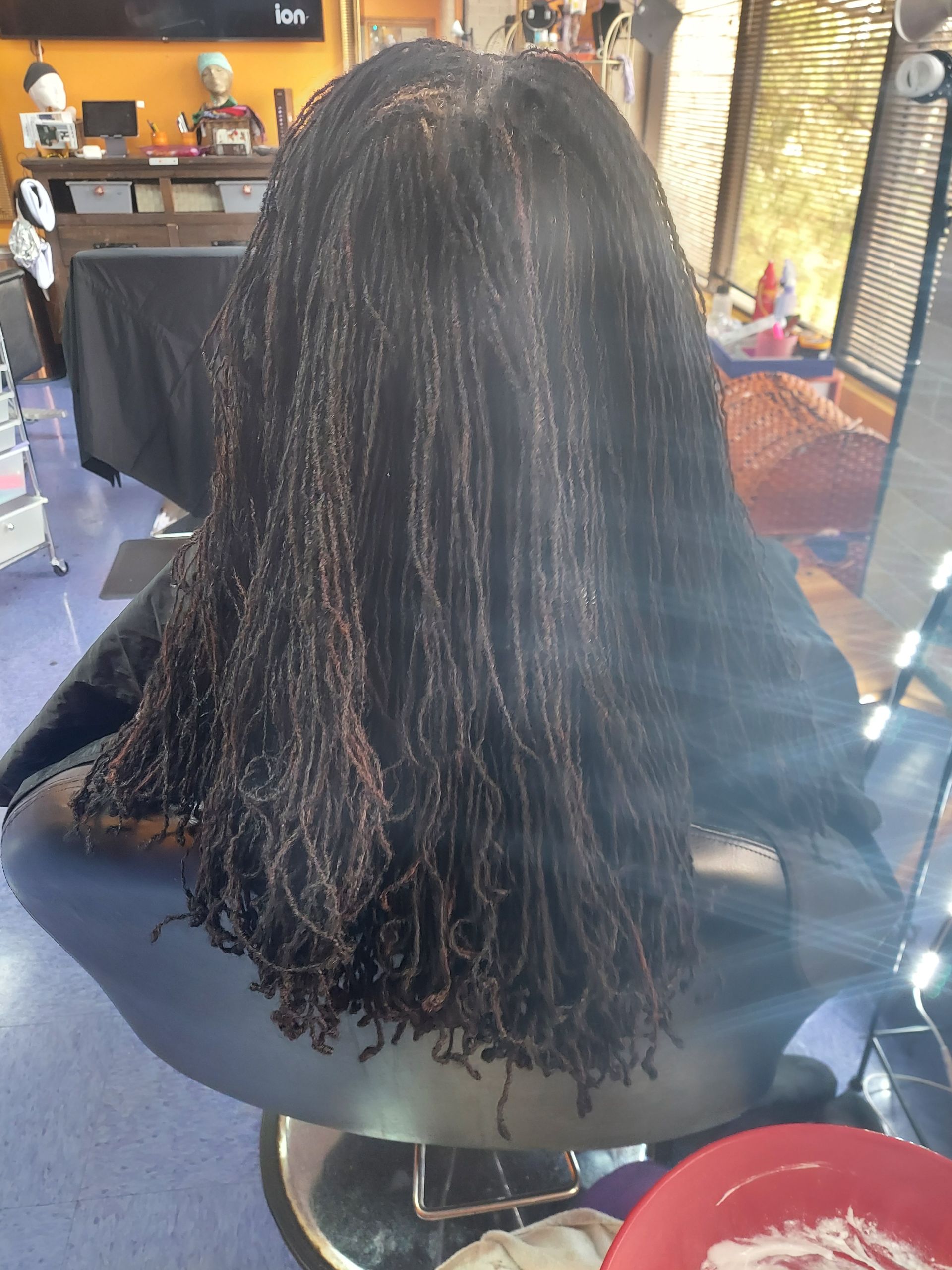 Woman in a salon chair with long, dark micro braids.