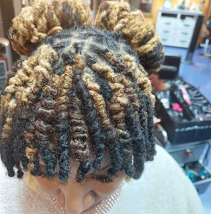 Woman with black and blonde locs styled in space buns at a salon.