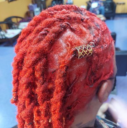 Person's head with vibrant red locs and a hair accessory in a salon setting.