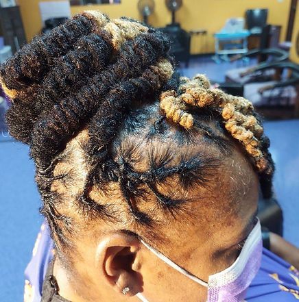 Woman with black and blonde locs updo, wearing a mask, in a salon.