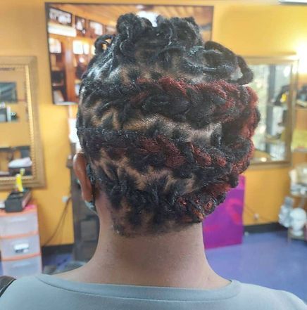 Person with locs styled in a zig-zag pattern, with red highlights. Indoors with yellow wall, mirror.